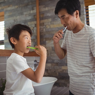 a father and son brushing their teeth together