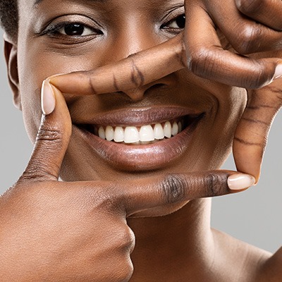 Nose-to-neck closeup of a woman smiling with half of her teeth whitening to show the before/after results